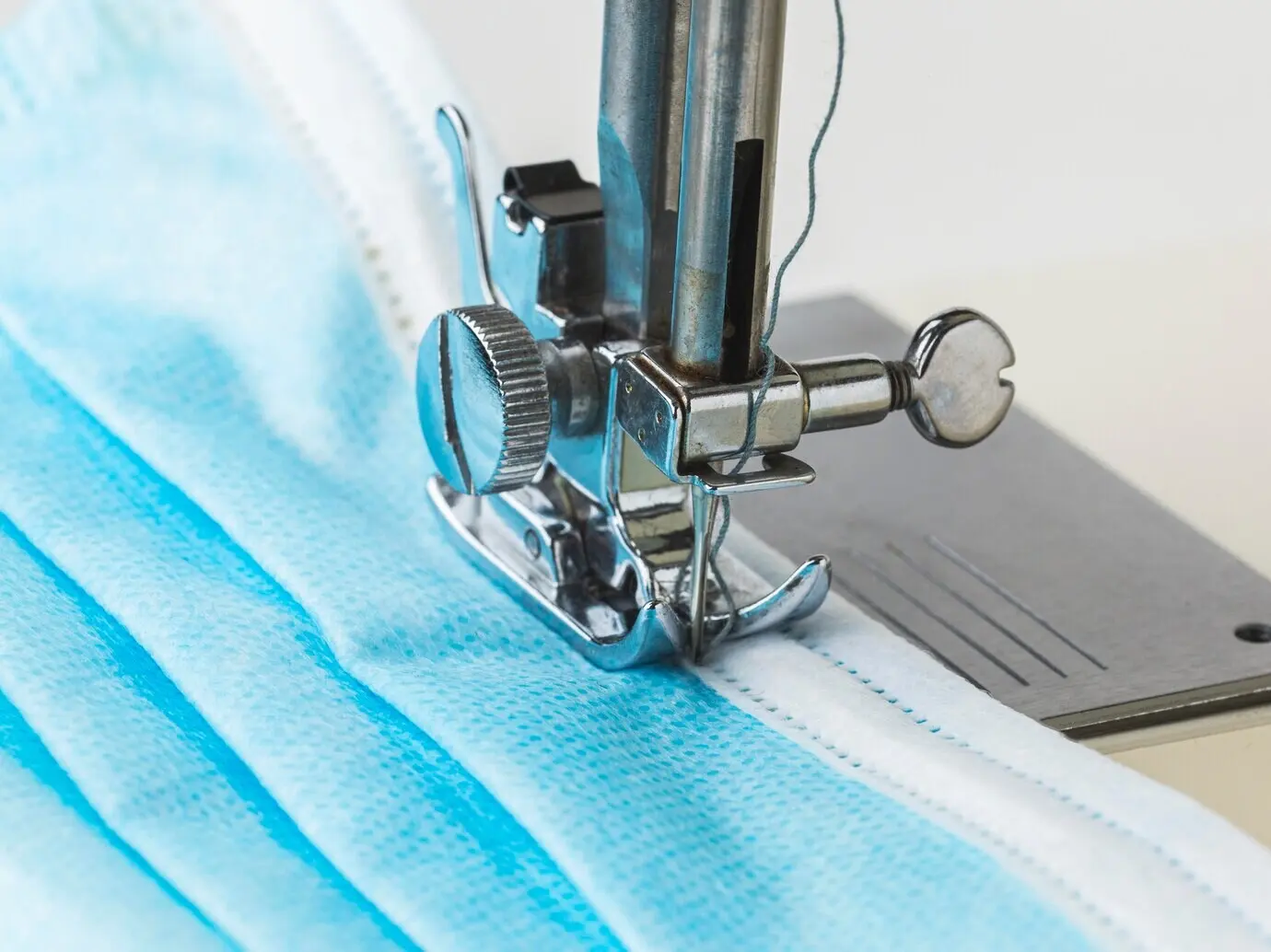 Nähmaschine und medizinische Maske in Nahaufnahme.